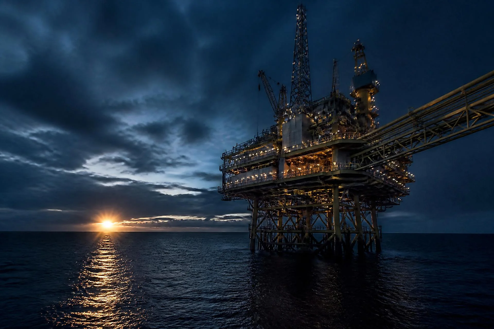 Plataforma offshore de petróleo e gás em operação ao anoitecer, com o mar ao redor